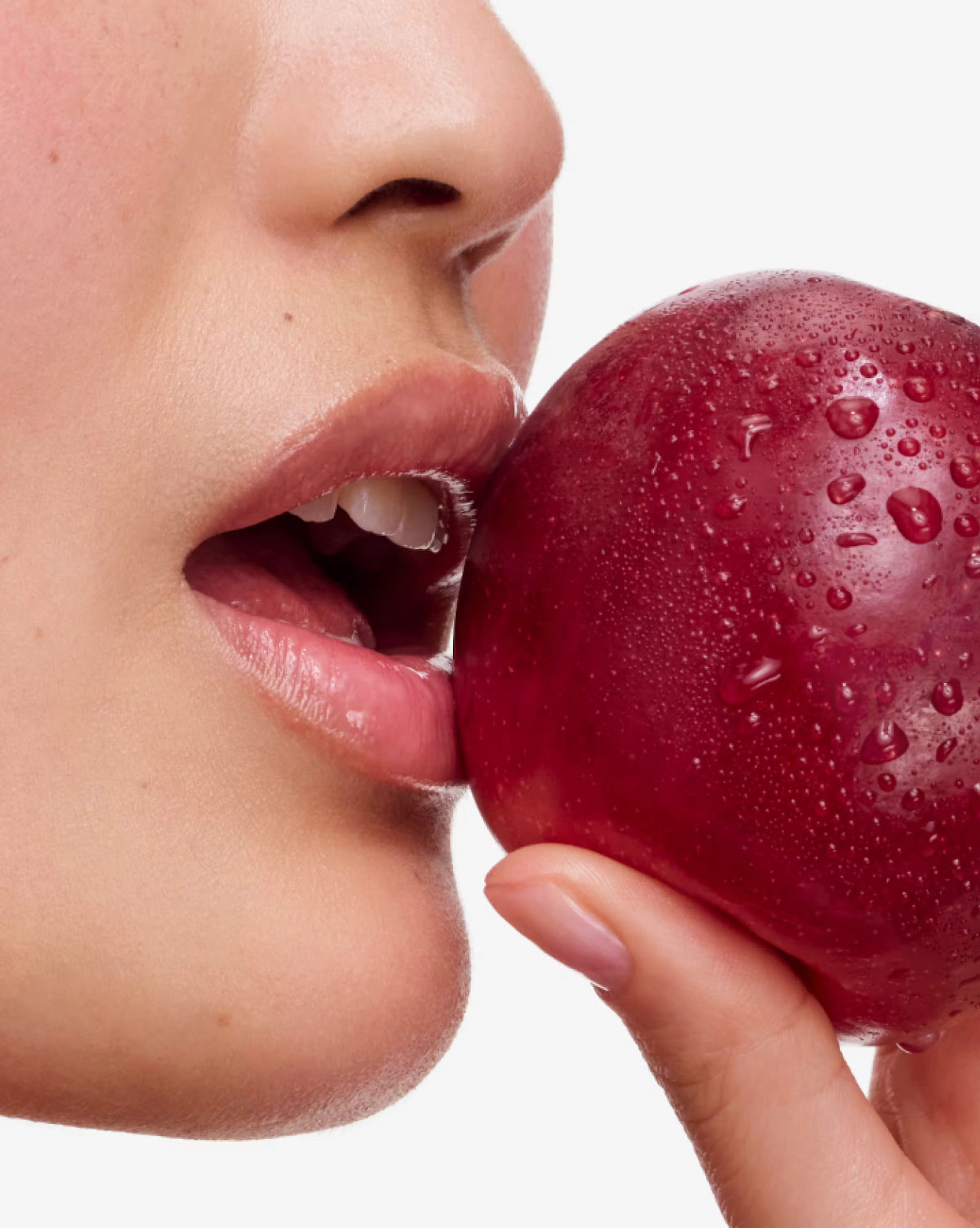 A close crop of lips about to bite a red apple