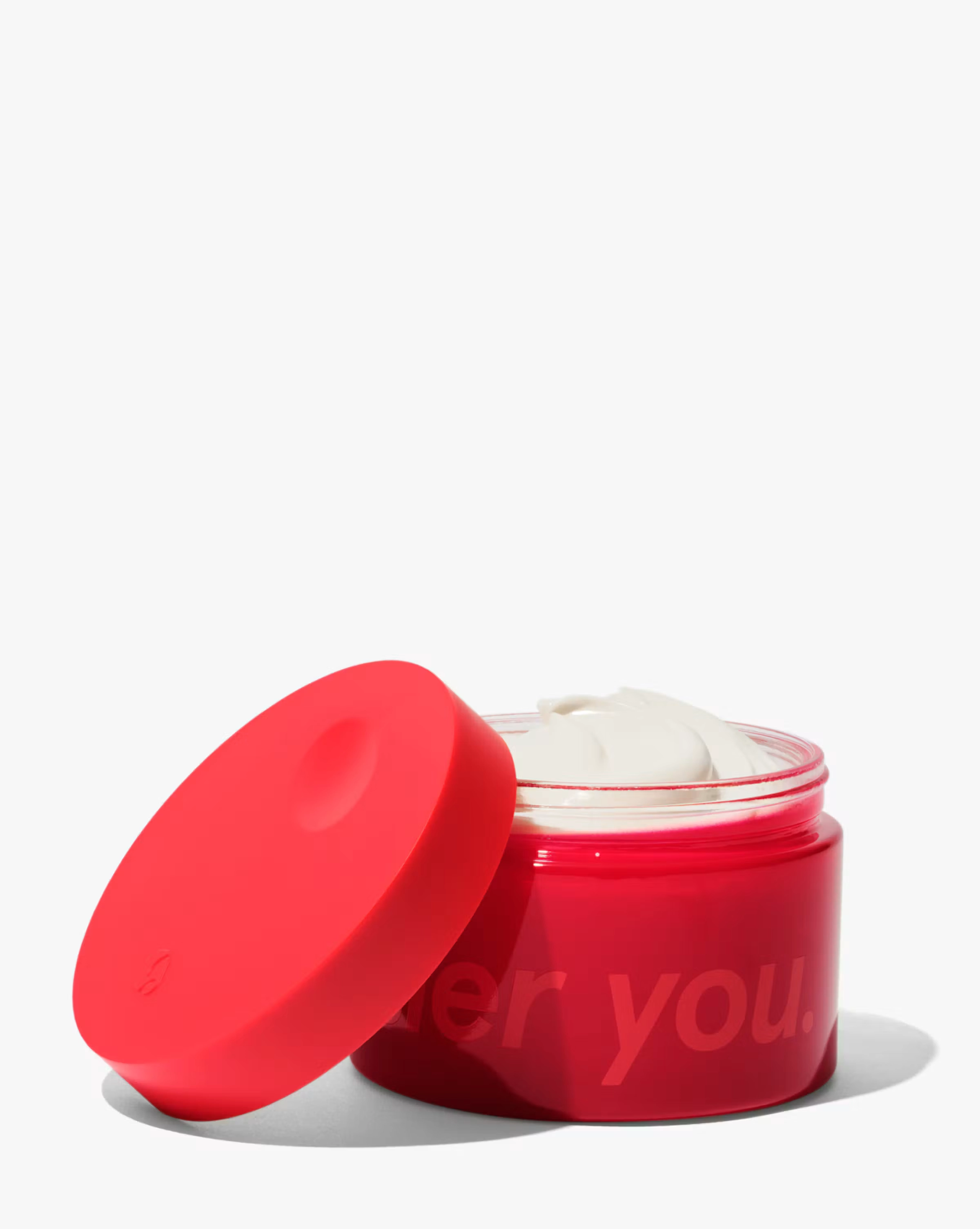 Crème de You jar with a red lid on a pale background