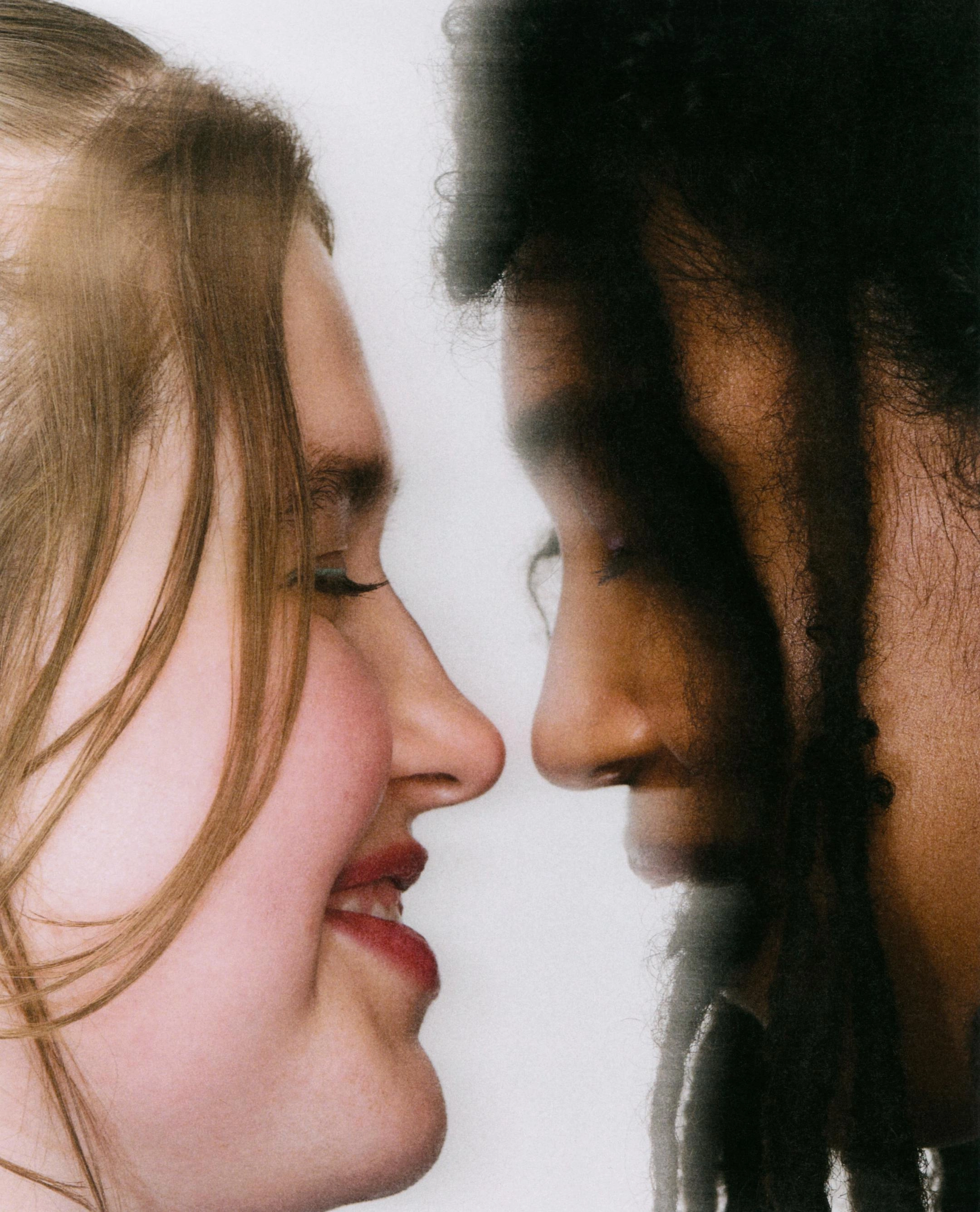 Two faces in profile almost touching, one with red hair and one with dark curls, from the About page